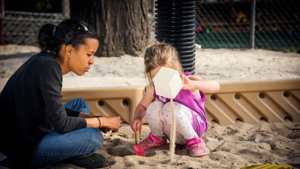 A teacher interacts with a student as they play outside