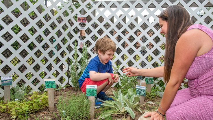 Master’s student and preschool teacher Kathy Spivey plays with a child in part of the new sensory garden at UNC Greensboro’s Child Care Education Program.