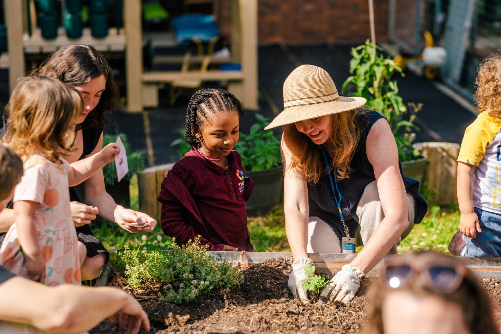 Adult and children planting seeds.